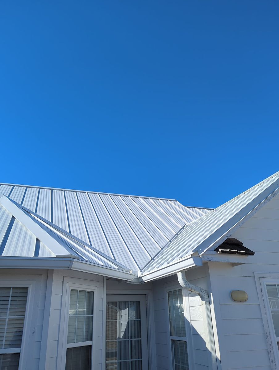 A white house with a metal roof and a blue sky in the background.