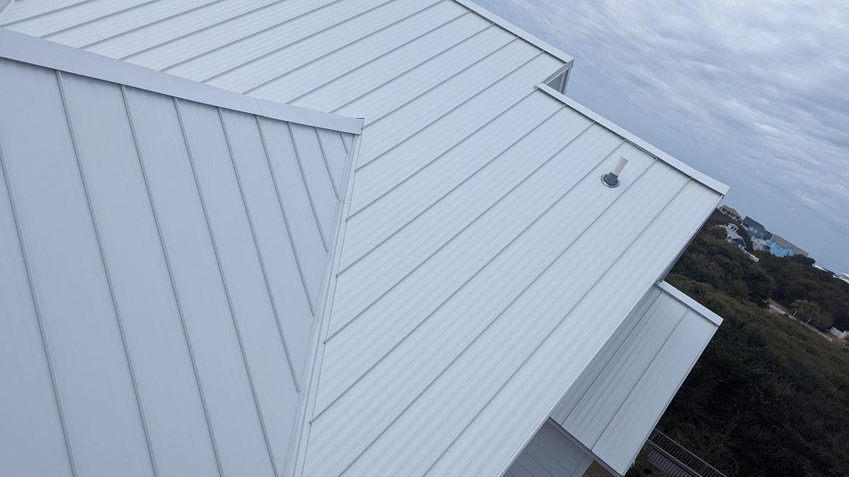 A white house with a white roof is sitting on top of a hill.
