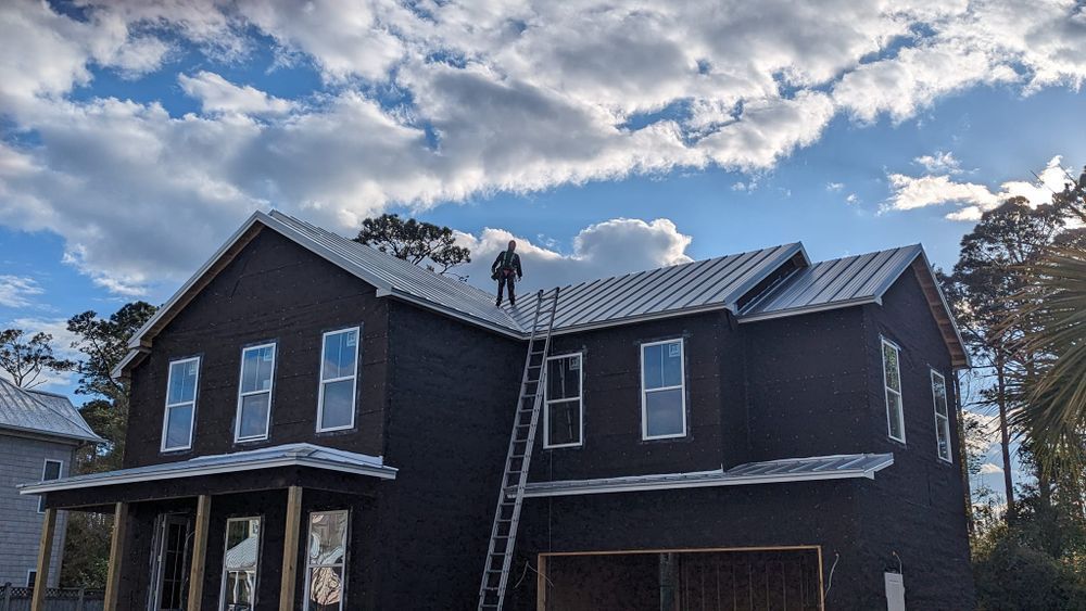 A man is standing on the roof of a house under construction.