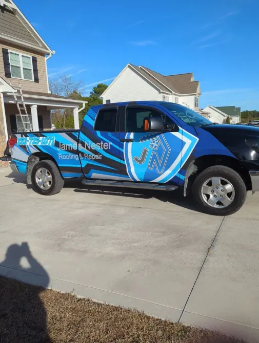 A blue and black truck is parked in front of a house.