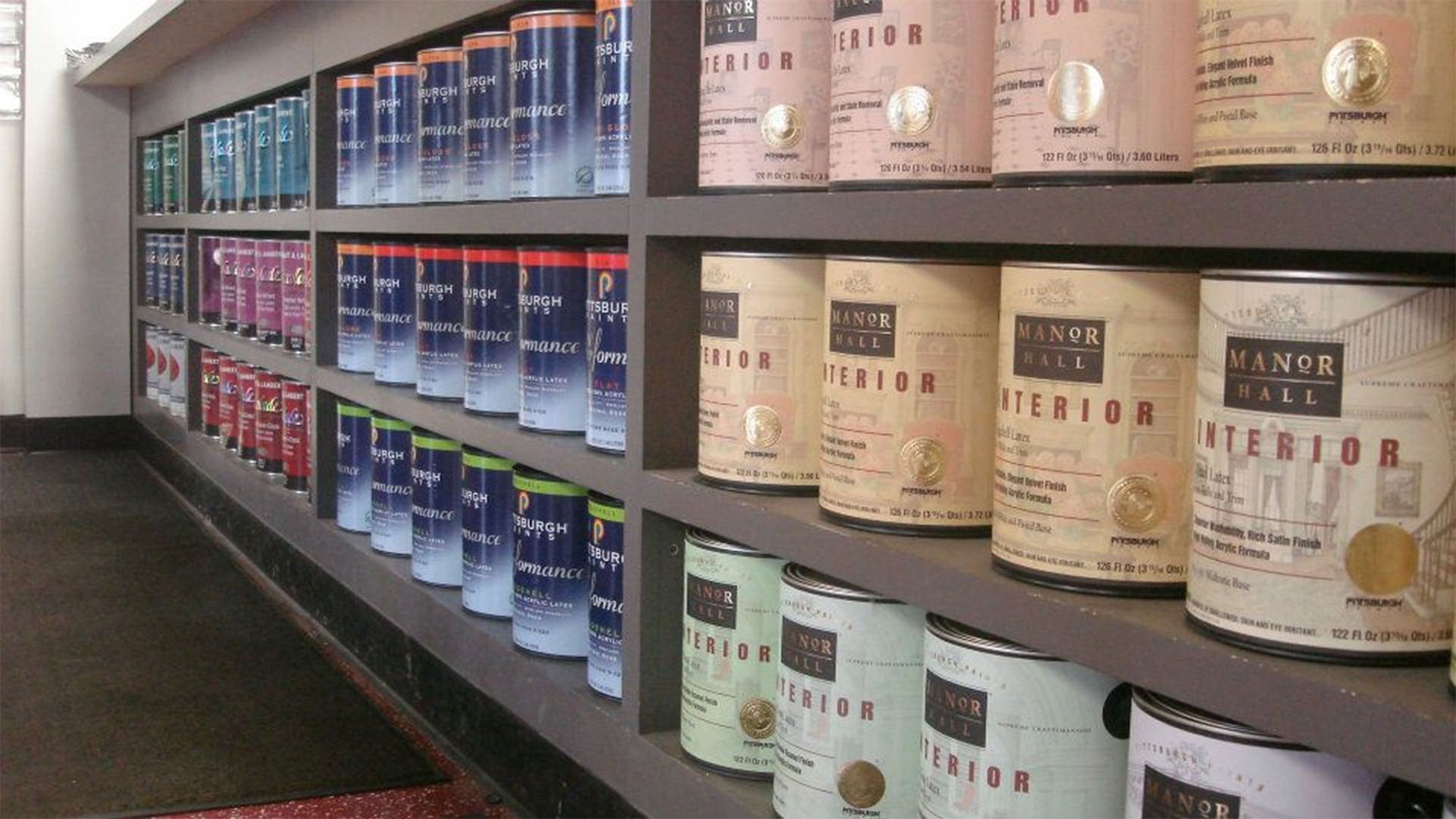 Shelves filled with neatly arranged, multi-colored paint cans in a retail store.