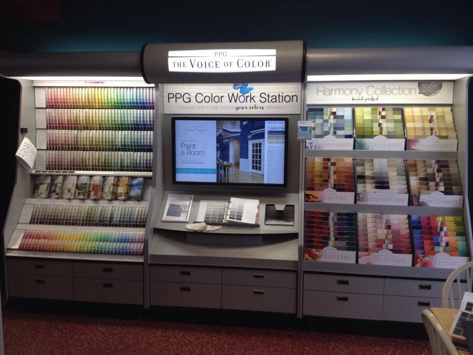 A PPG paint color display stand featuring rows of paint chips, a central digital screen, and a Harmony collection display.