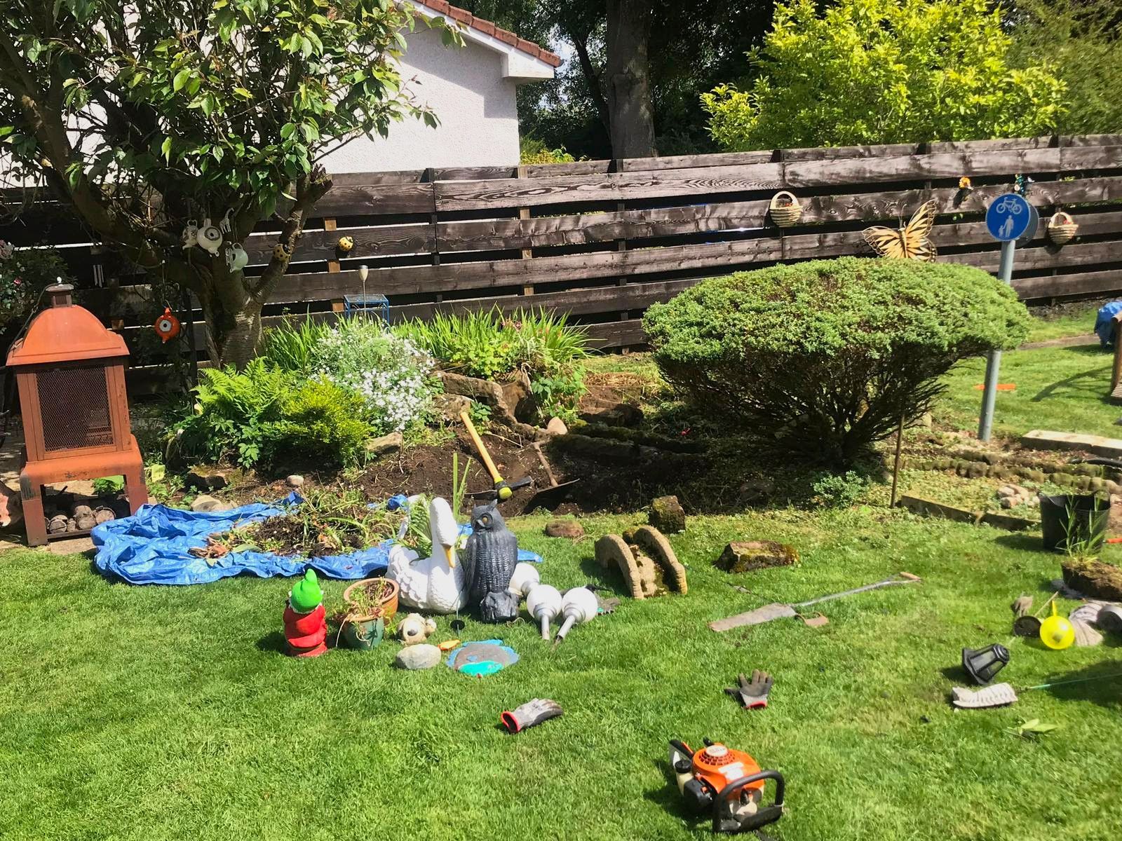 A lawn with a lot of tools and a fence in the background.
