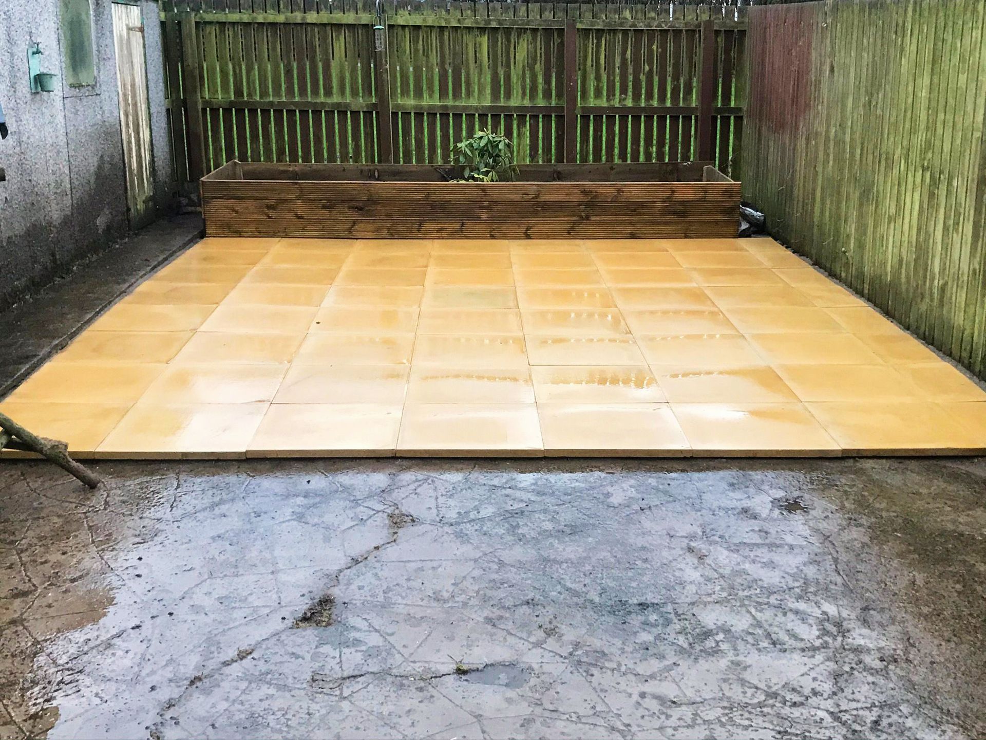 A concrete patio with a wooden fence in the background.