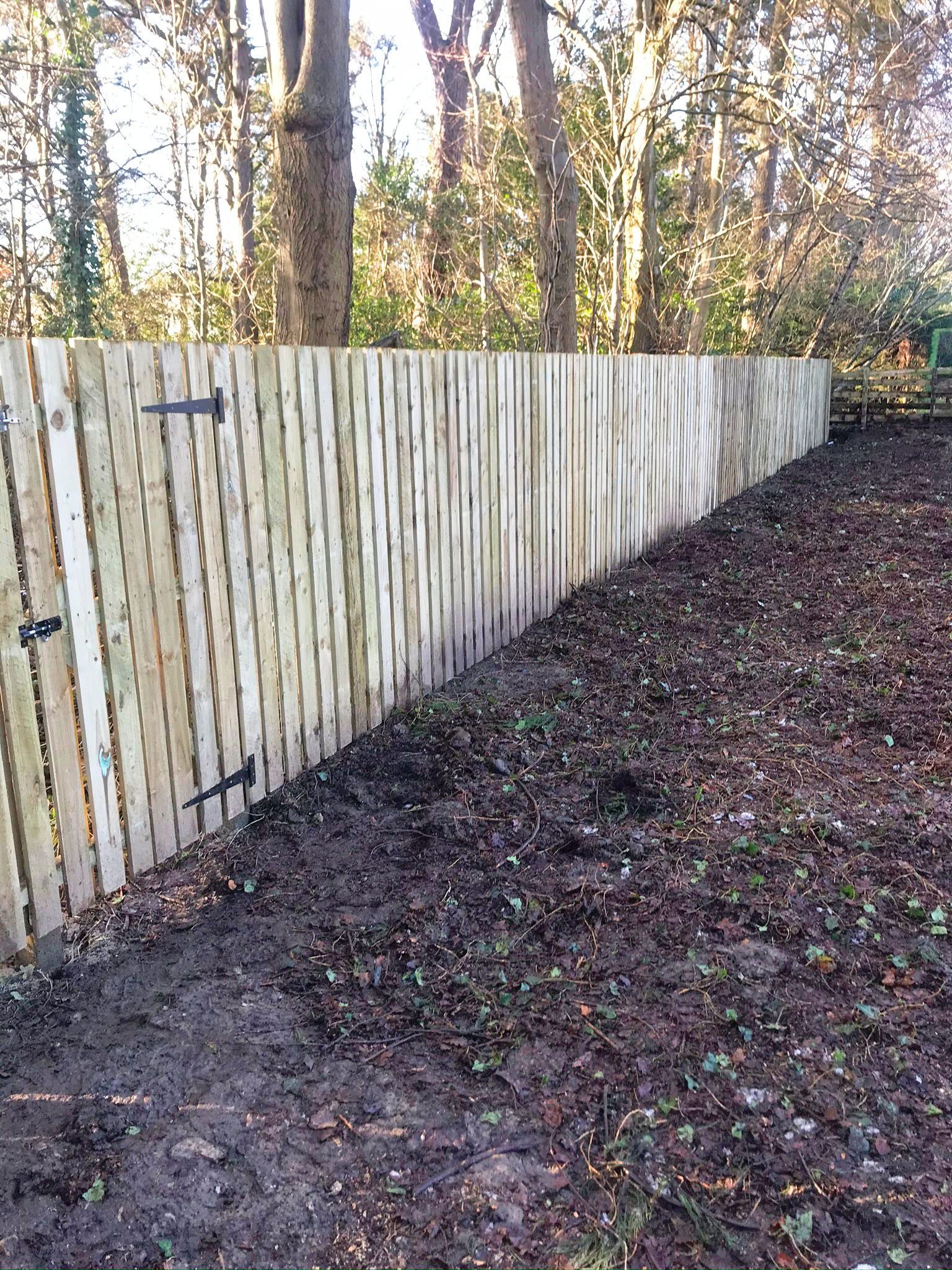 A wooden fence is surrounded by trees in the woods.