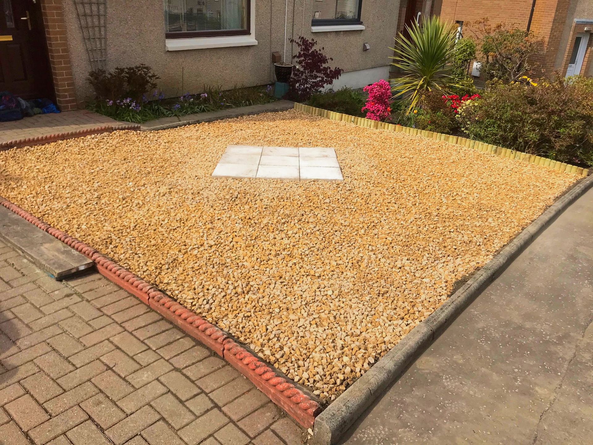 A complete refresh of a front-garden with soil covering stones and a few slabs for planters.