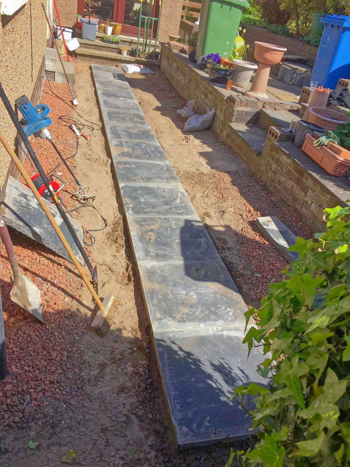A concrete walkway is being built in a garden.