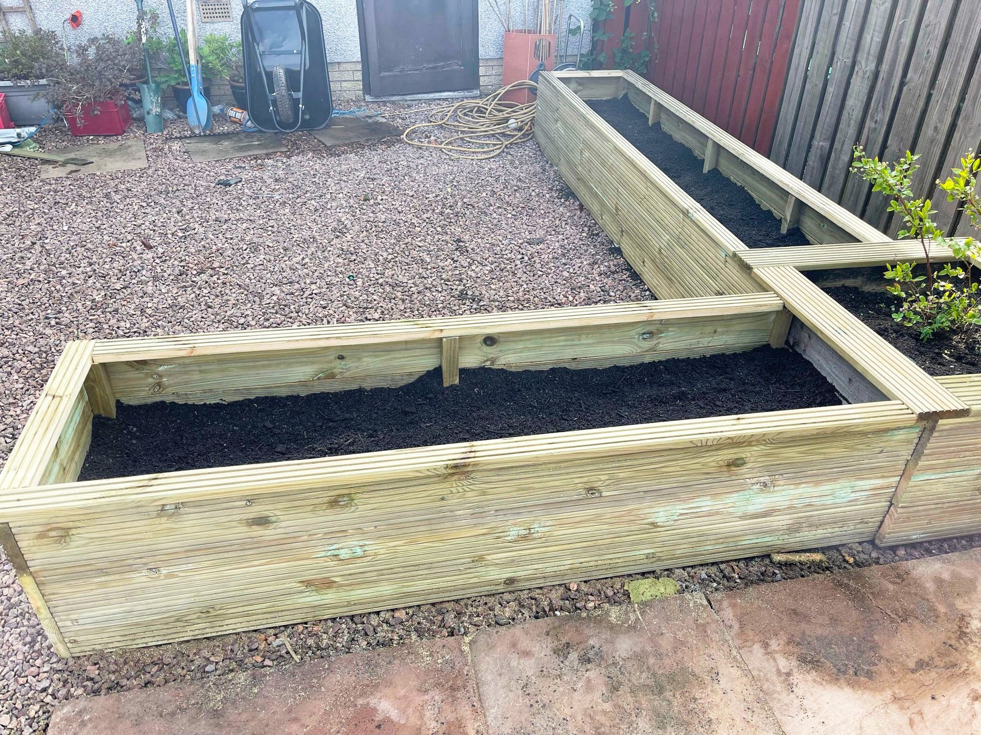 A couple of wooden planters sitting on top of a gravel driveway.