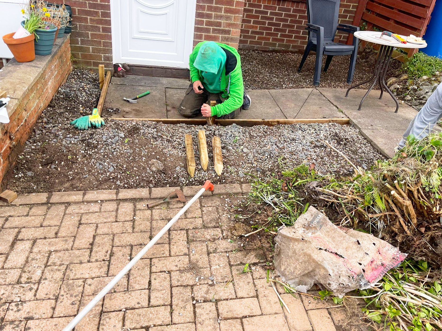 A man is kneeling on a patio working on an astro turf.