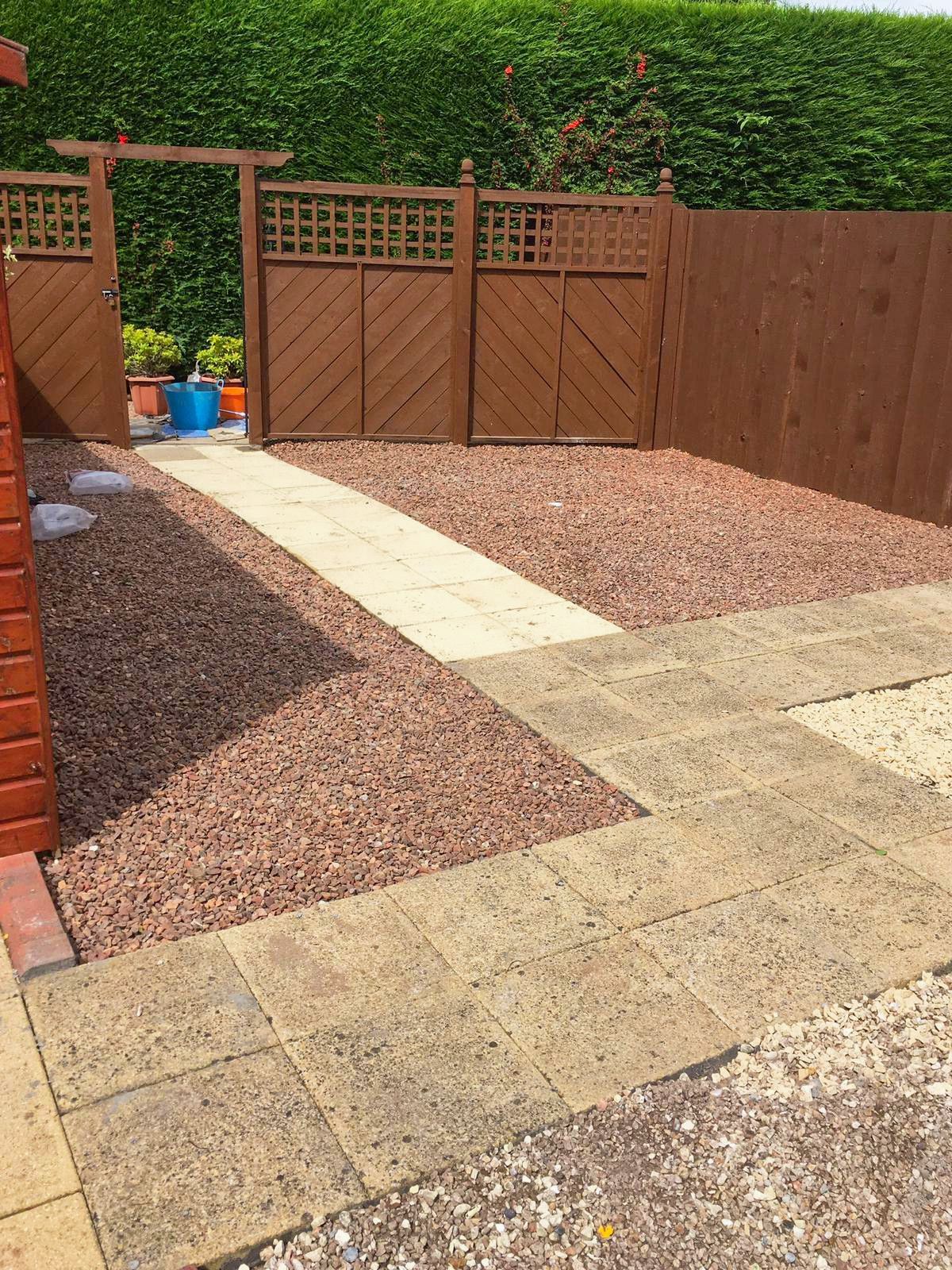 A patio with a wooden fence and gravel.