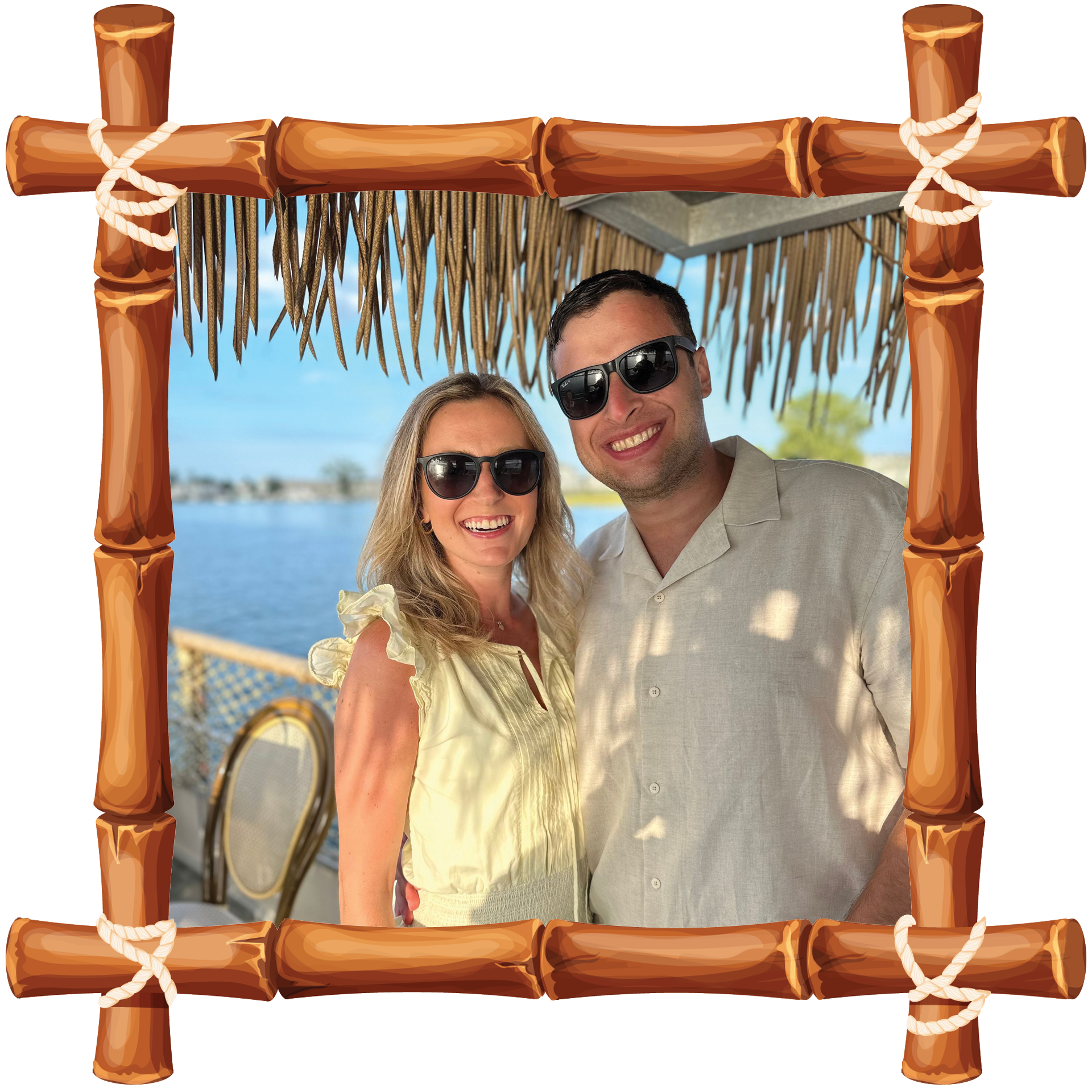Smiling couple in sunglasses posing in a tropical bamboo frame by the water