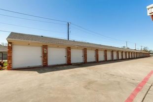 Hallway of storage units with white doors and ceiling lights.