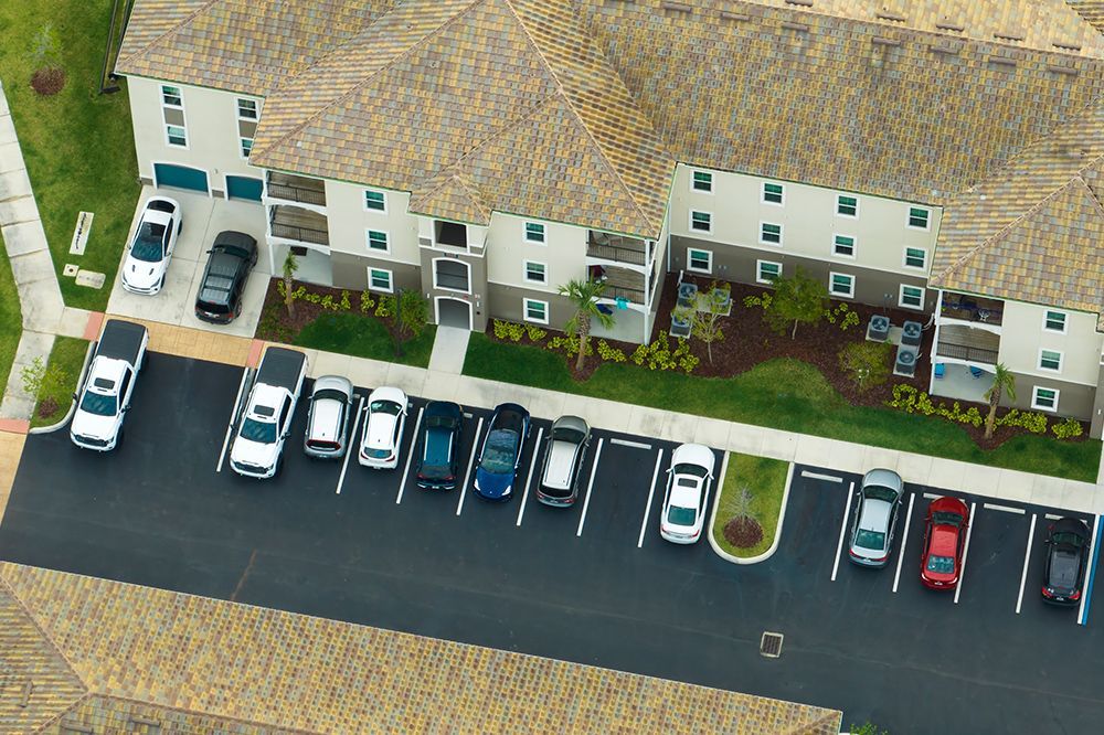 An aerial view of a parking lot with cars parked in front of a building.