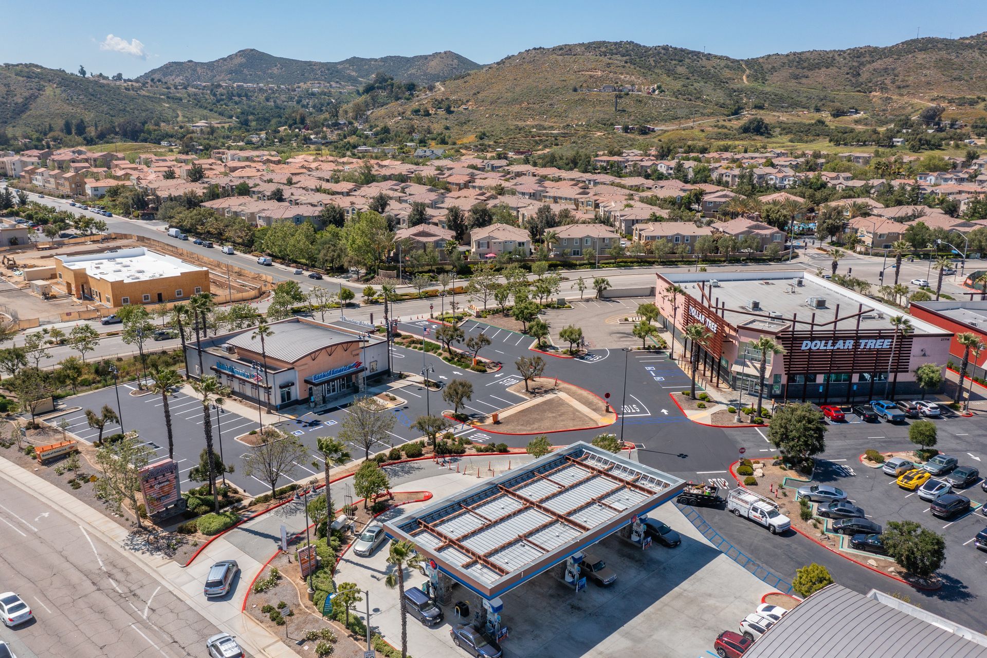 An aerial view of a gas station in a city with mountains in the background.