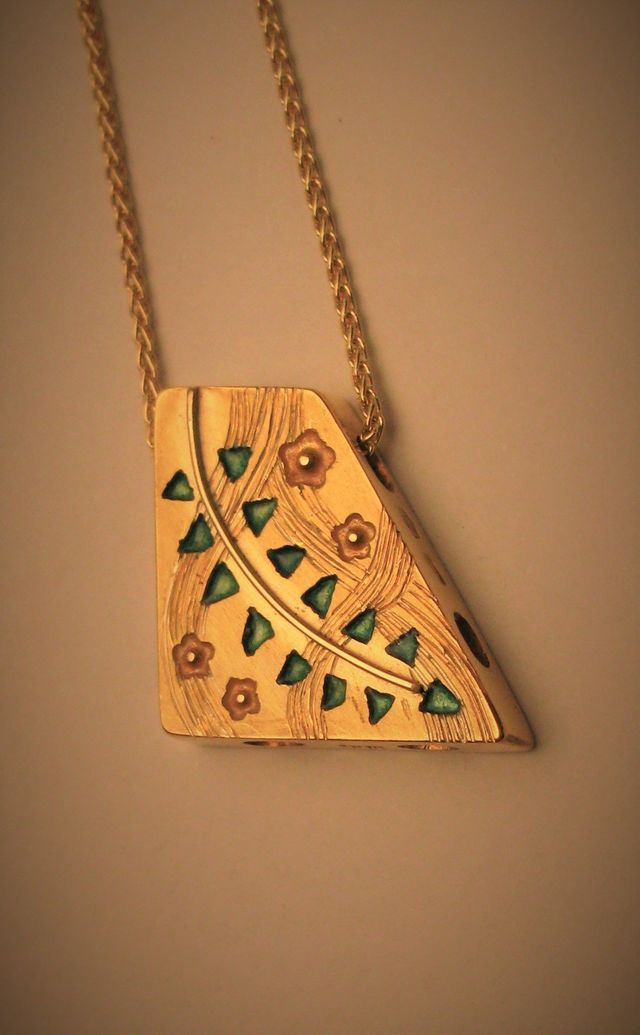 ciondolo d'oro con piccoli fiori e triangoli verdi