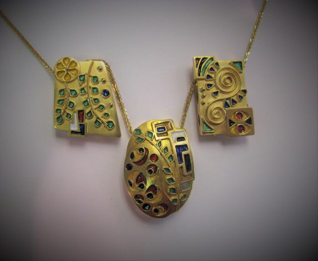 collana con tre ciondoli d'oro con dettagli colorati