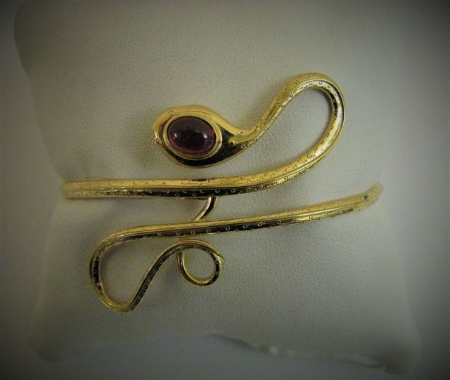 gioiello in oro con forme sinuose e pietra preziosa