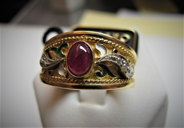 anello in oro con fregi verdi e pietra centrale