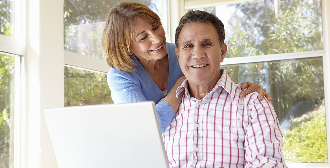 a man and woman are smiling while looking at a laptop