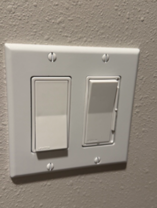 A hand holds electrical wires passing through a blue plastic junction box attached to a wooden wall stud in a building.