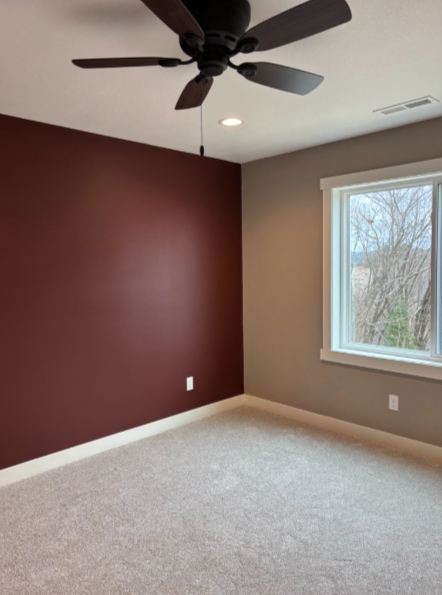 A ceiling fan with five metal blades and decorative textured inserts suspended from a white ceiling.