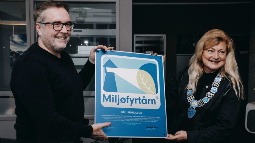Two people holding a blue poster, smiling. A man presents it to a woman in a building.