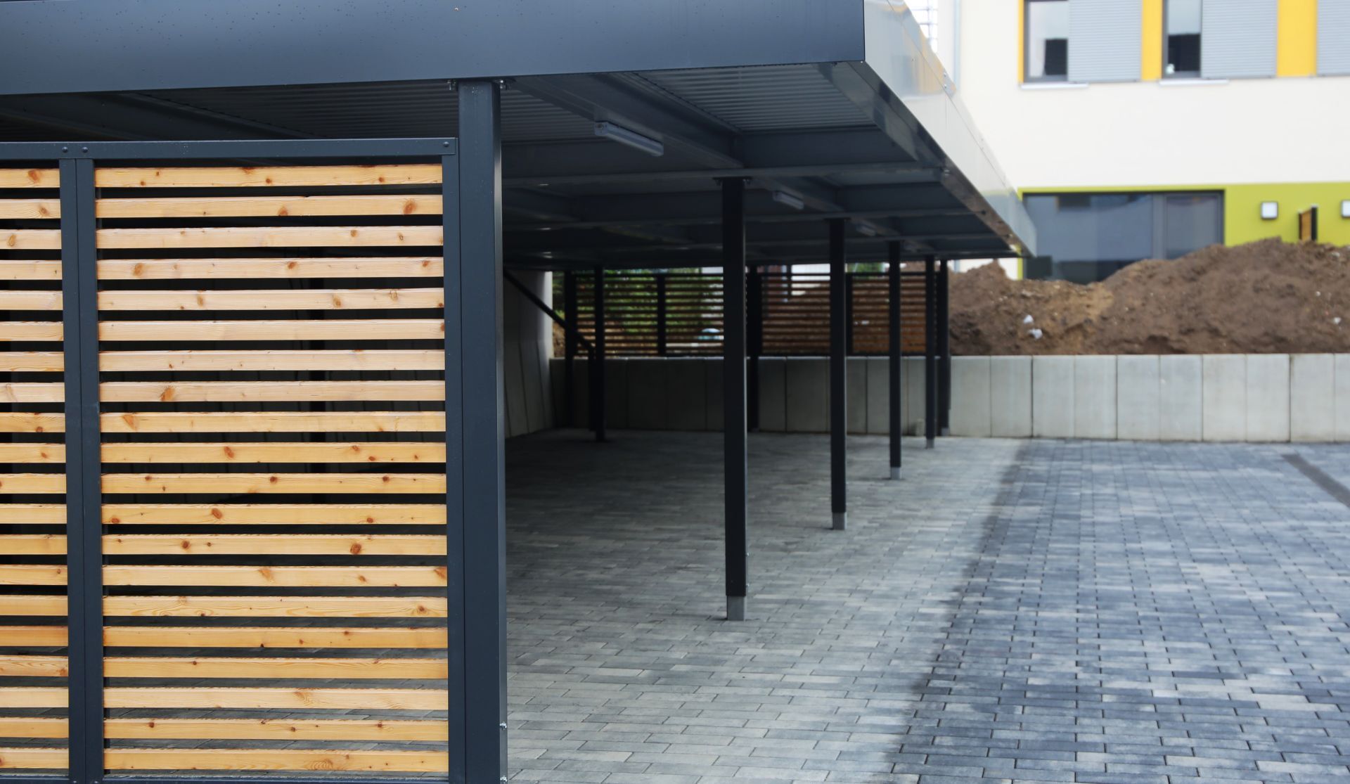 A carport with a wooden fence in front of a building.