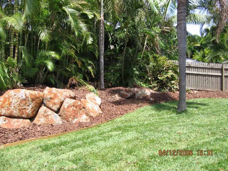 A Lush Green Lawn With A Fence And Palm Trees In The Background — Austen Landscaping & Earthmoving in Deeragun, QLD