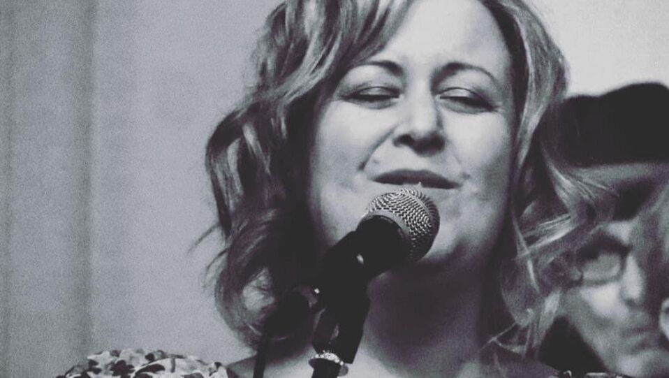 Black-and-white close-up of a singer smiling into a microphone on stage