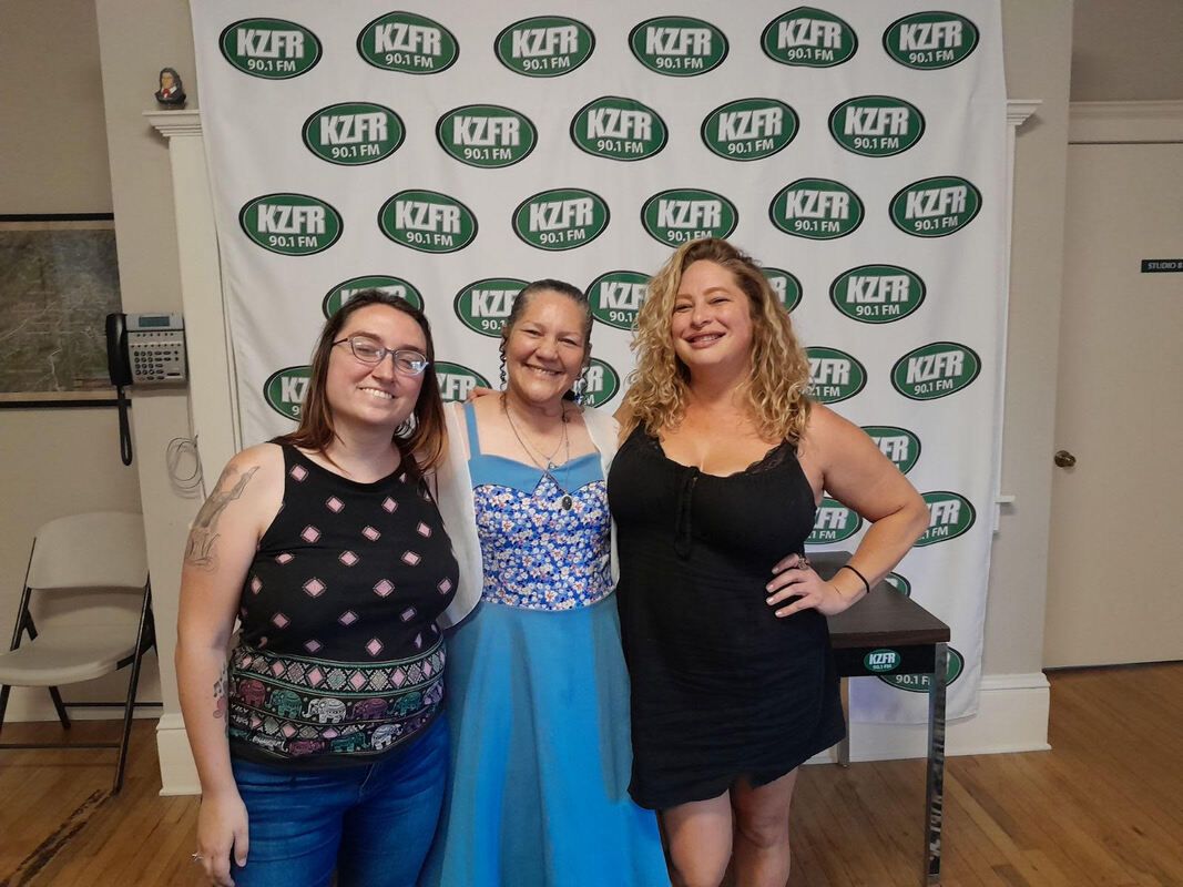Three people smiling in front of a KETP backdrop, posing at an indoor event.