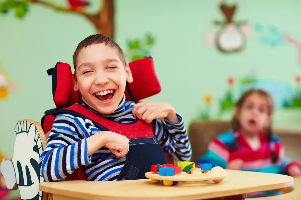A Smiling Child in a Specialized Chair Plays — CQ Home Care in Yeppoon, QLD