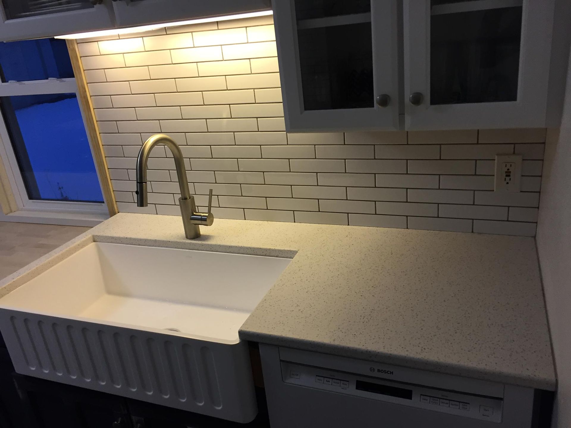 Kitchen with white sink, countertops, and subway tile backsplash; brushed nickel faucet.