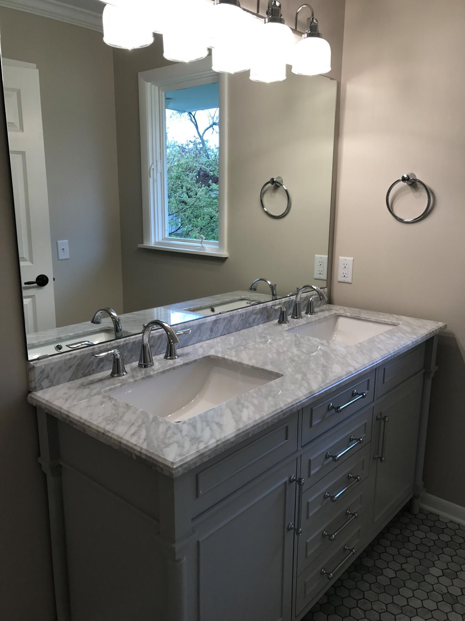 Bathroom with white vanity, marble countertop, large mirror, and chrome fixtures.