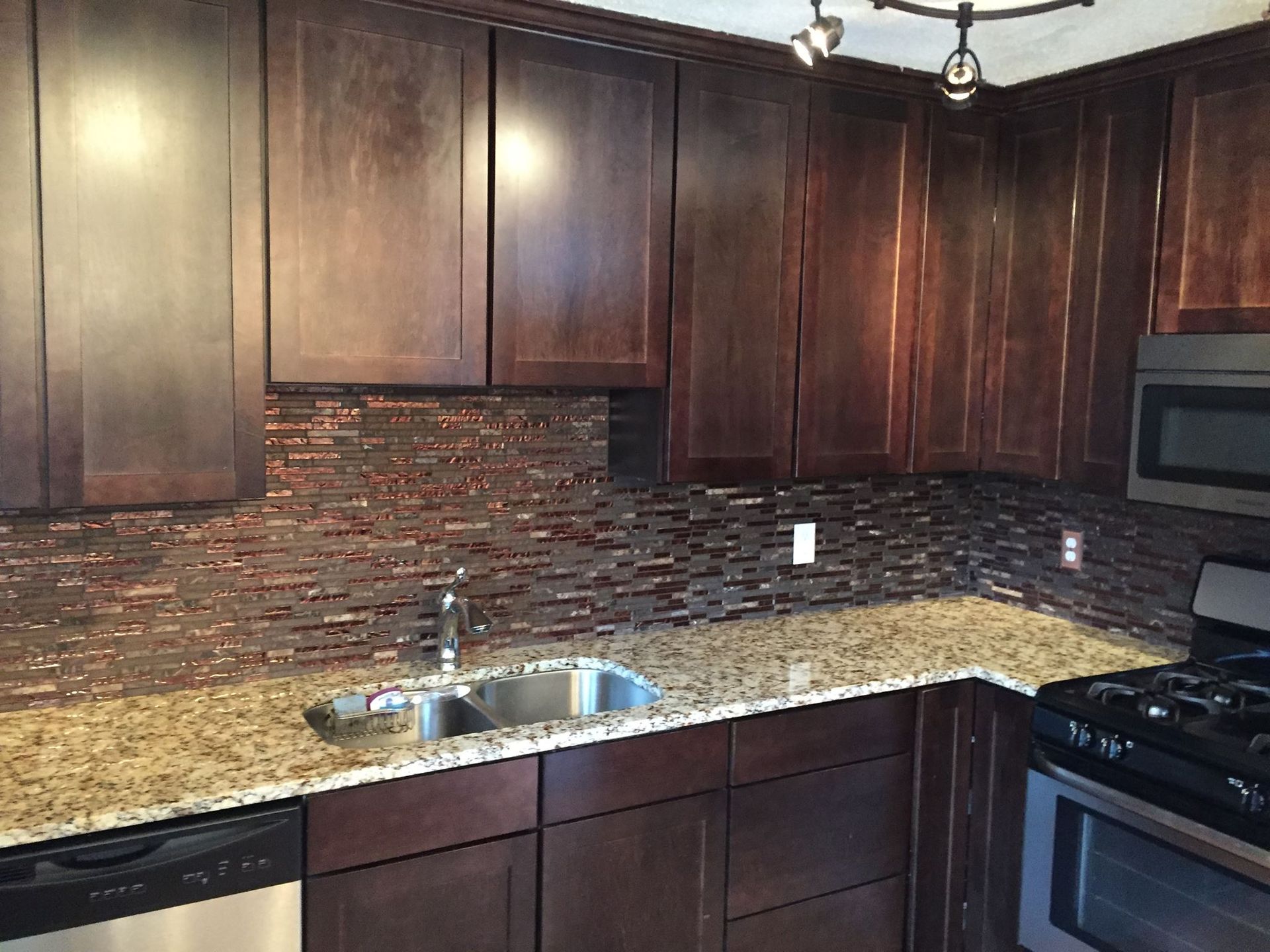 Kitchen with dark brown cabinets, granite countertops, and a mosaic tile backsplash.