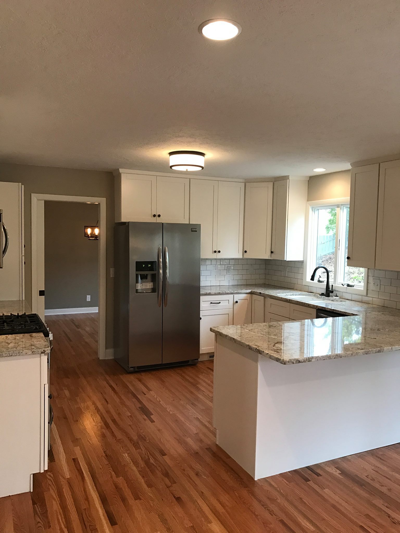 Modern kitchen with white cabinets, stainless steel refrigerator, and granite countertops.