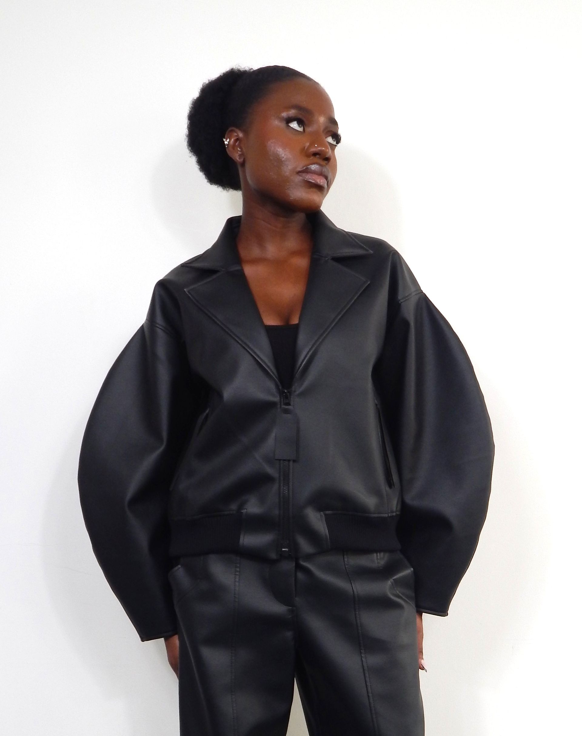 Woman in black leather jacket and pants, looking up.