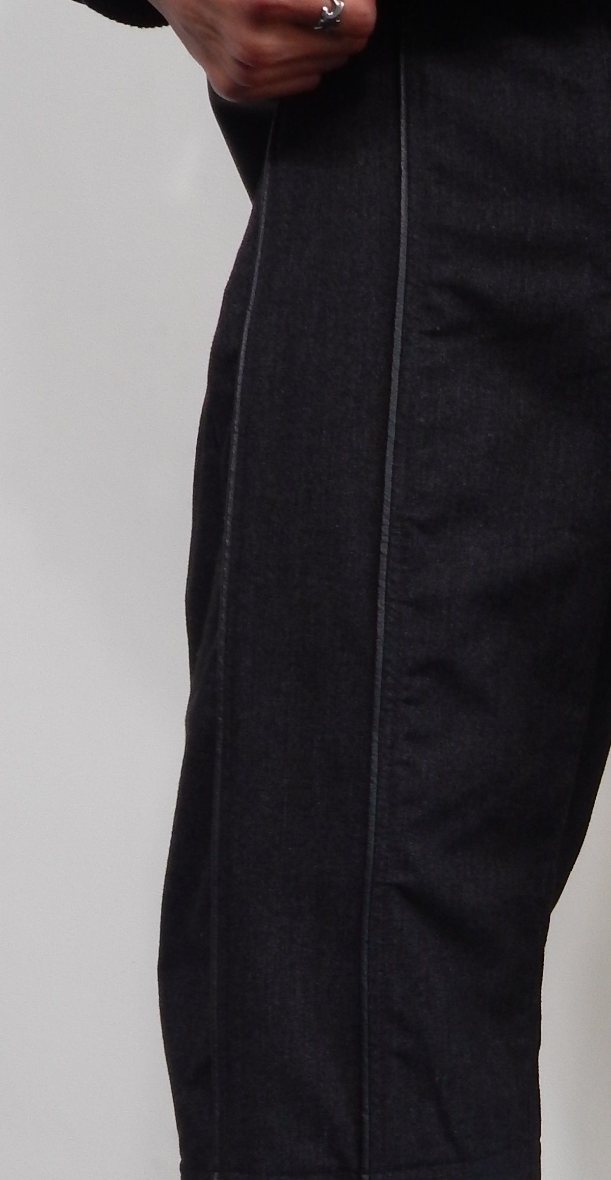 Close-up of a person's dark pants with a light-colored vertical seam down the side.