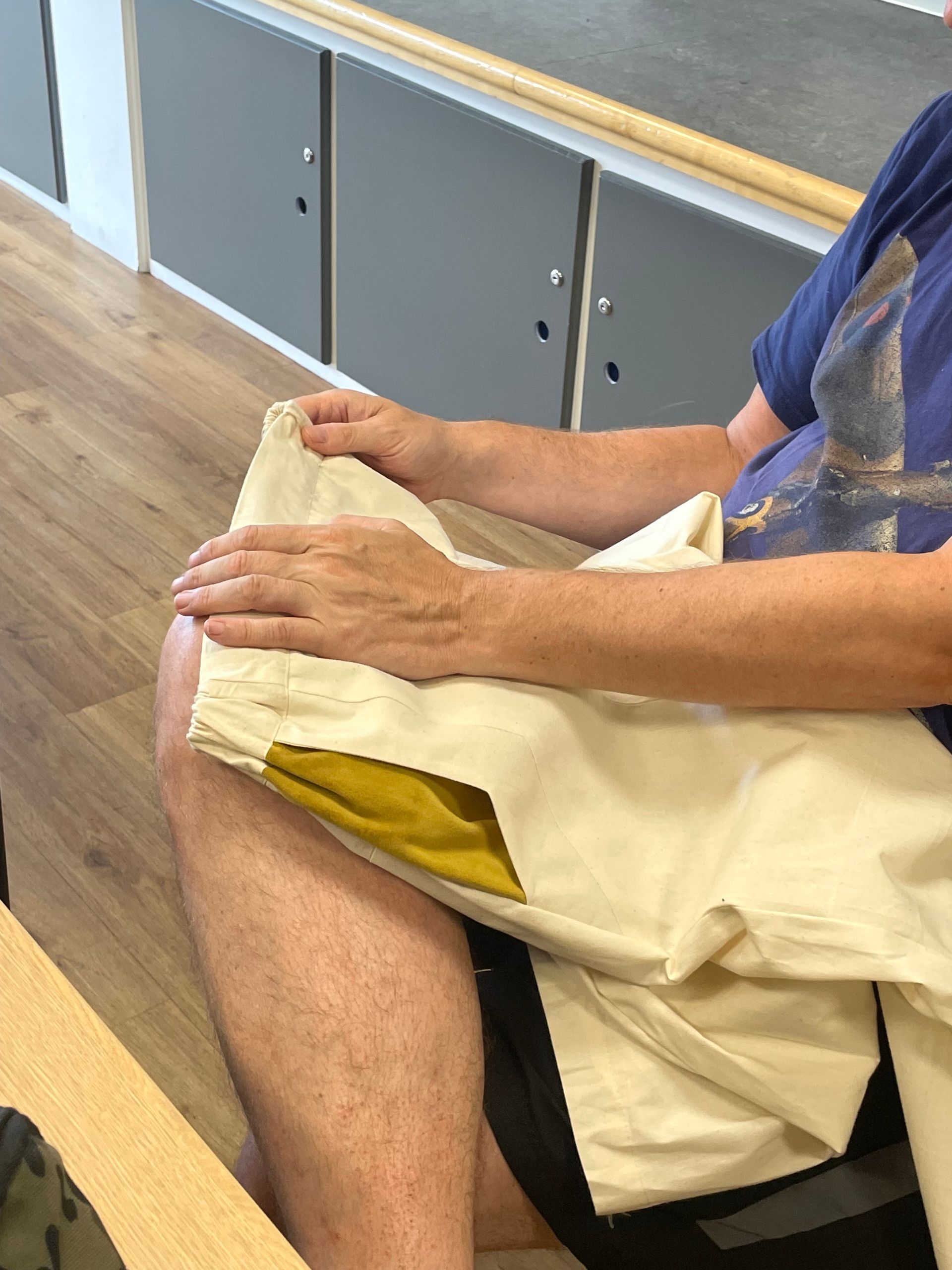 Person holding beige fabric, possibly a garment, with yellow lining.