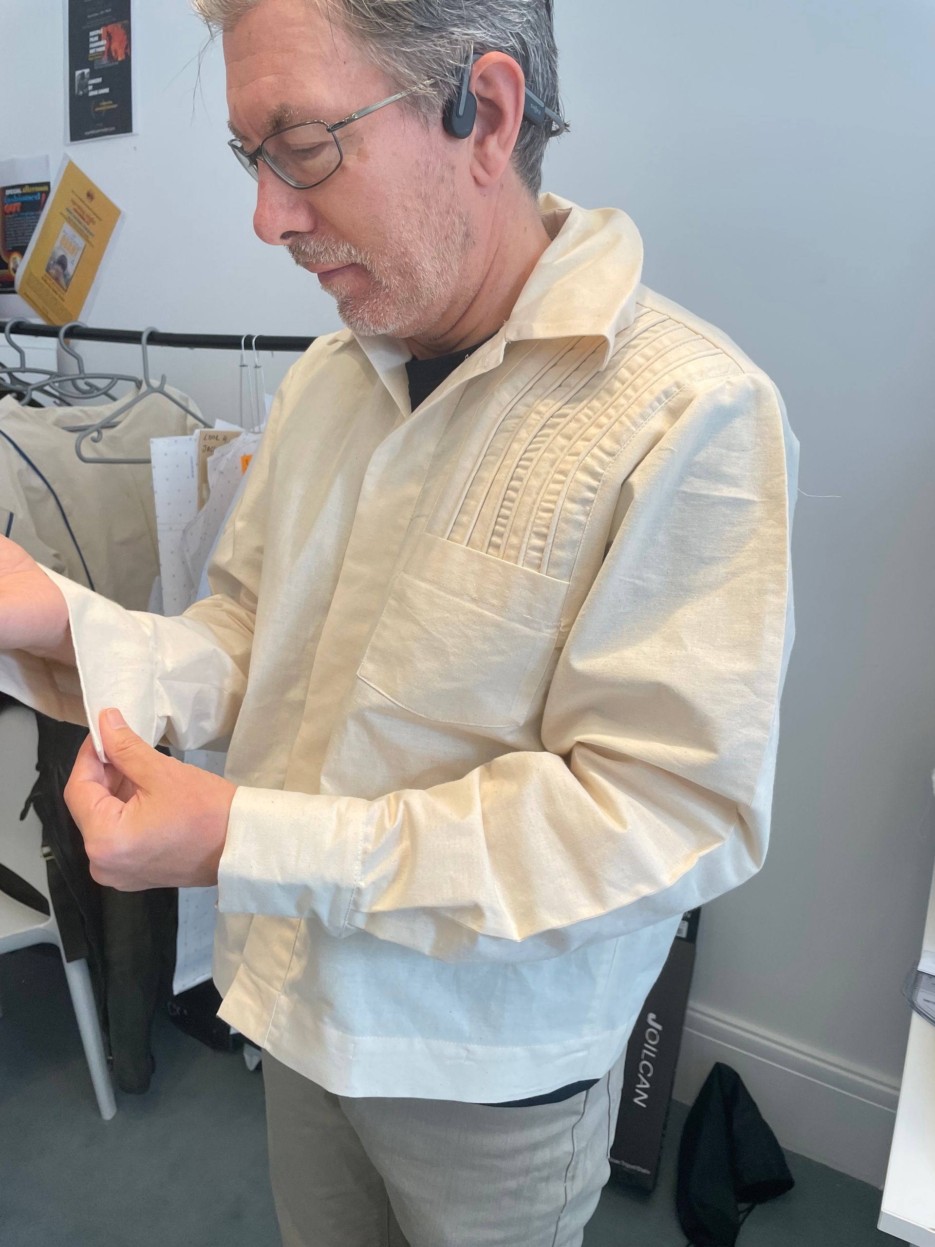 Person folding a pair of cream-colored pants on a wooden table.