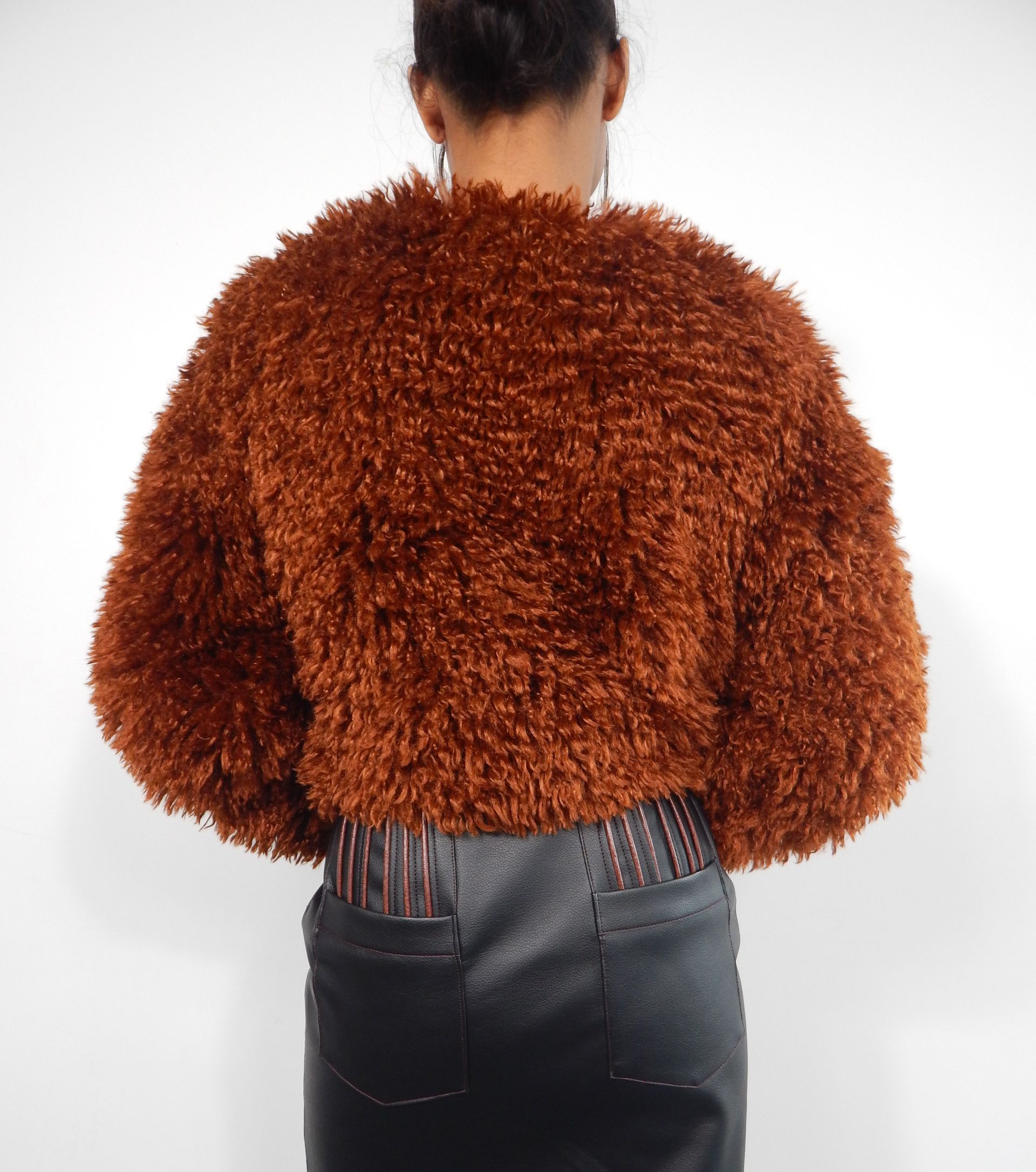 Back view of a person wearing a fuzzy brown jacket and dark skirt.