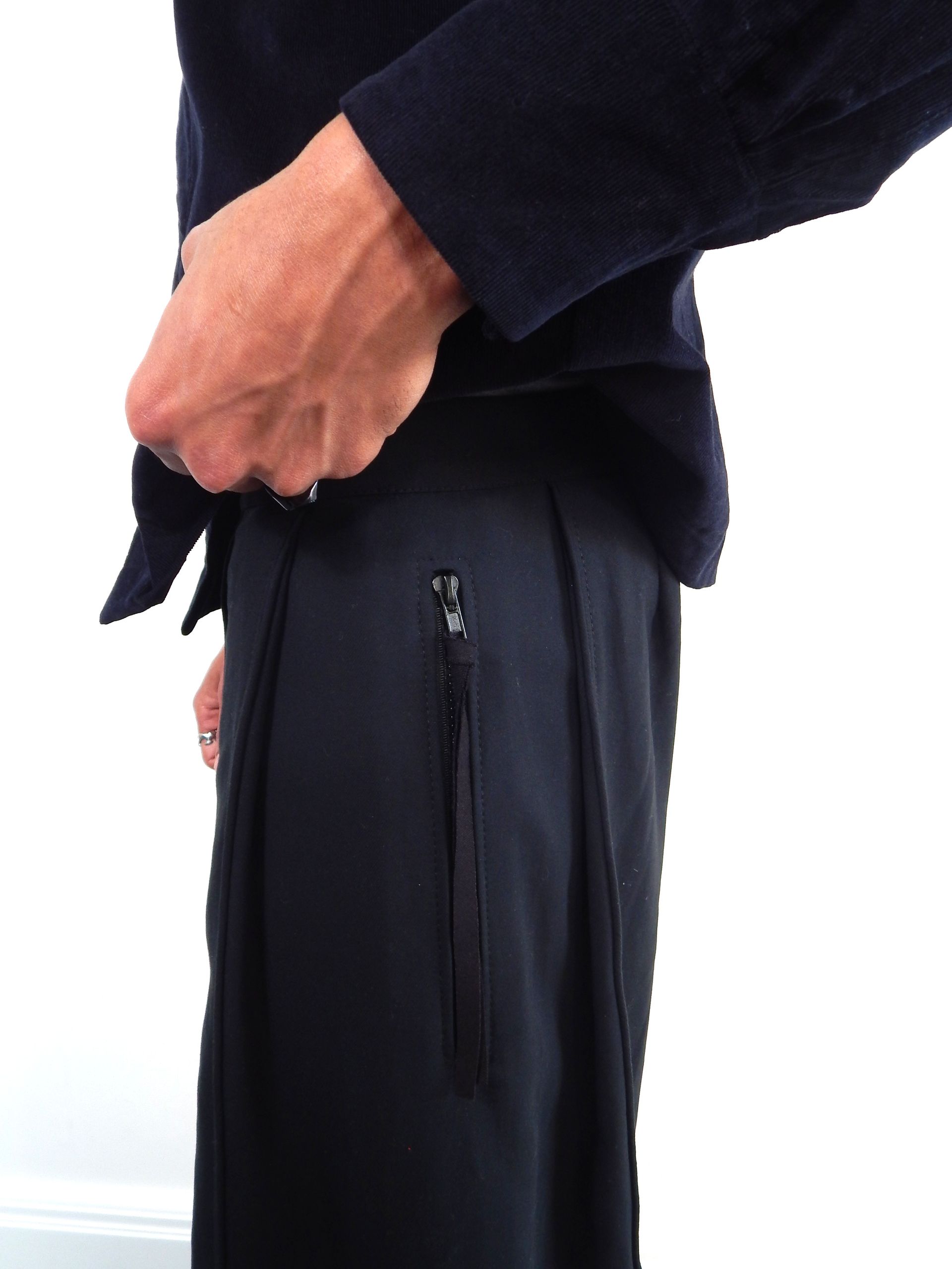 Person adjusting zipper on a dark navy skirt. A dark navy jacket is also visible.