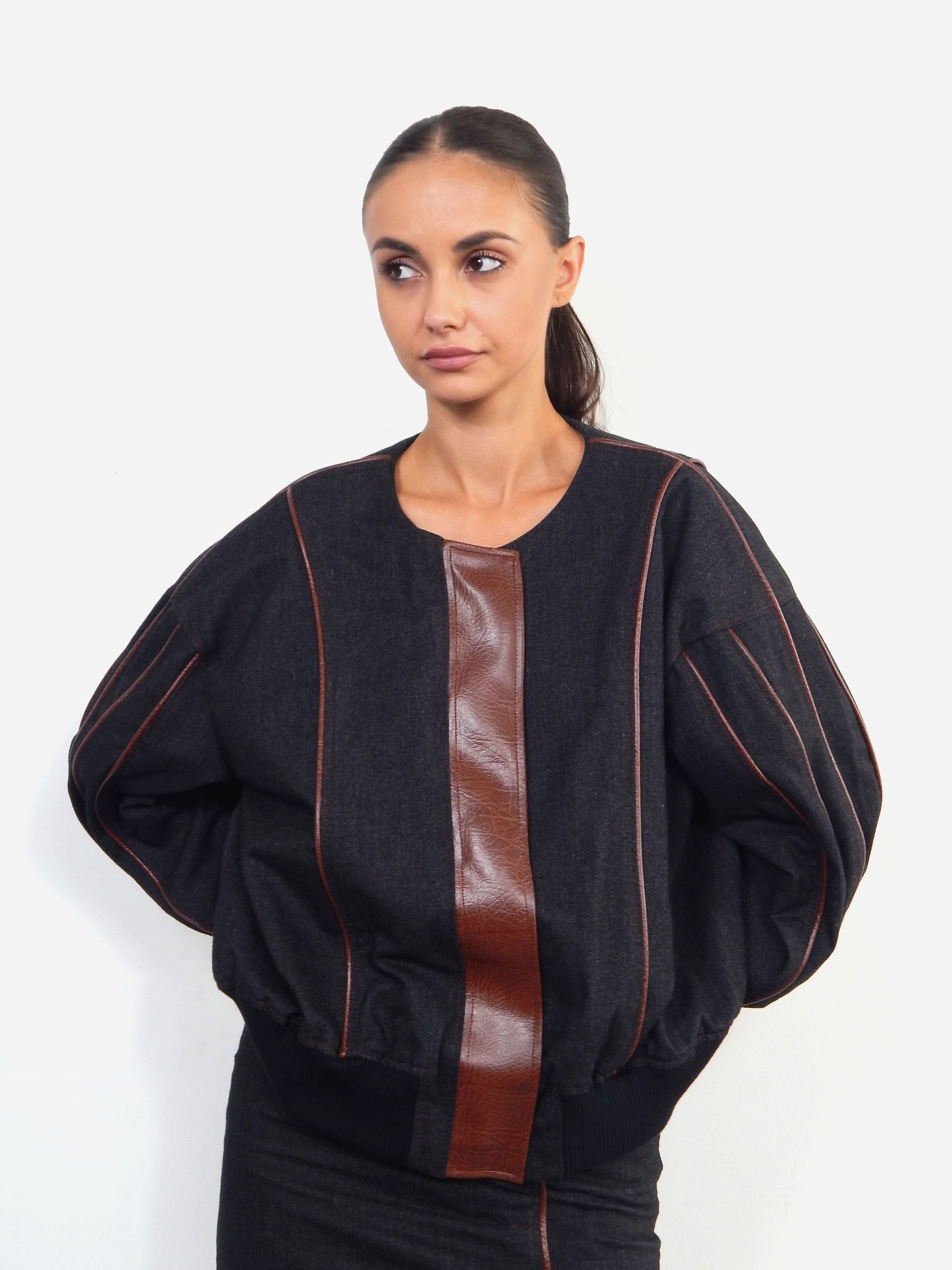 Woman in dark sweater with brown leather panel and lines, posing.