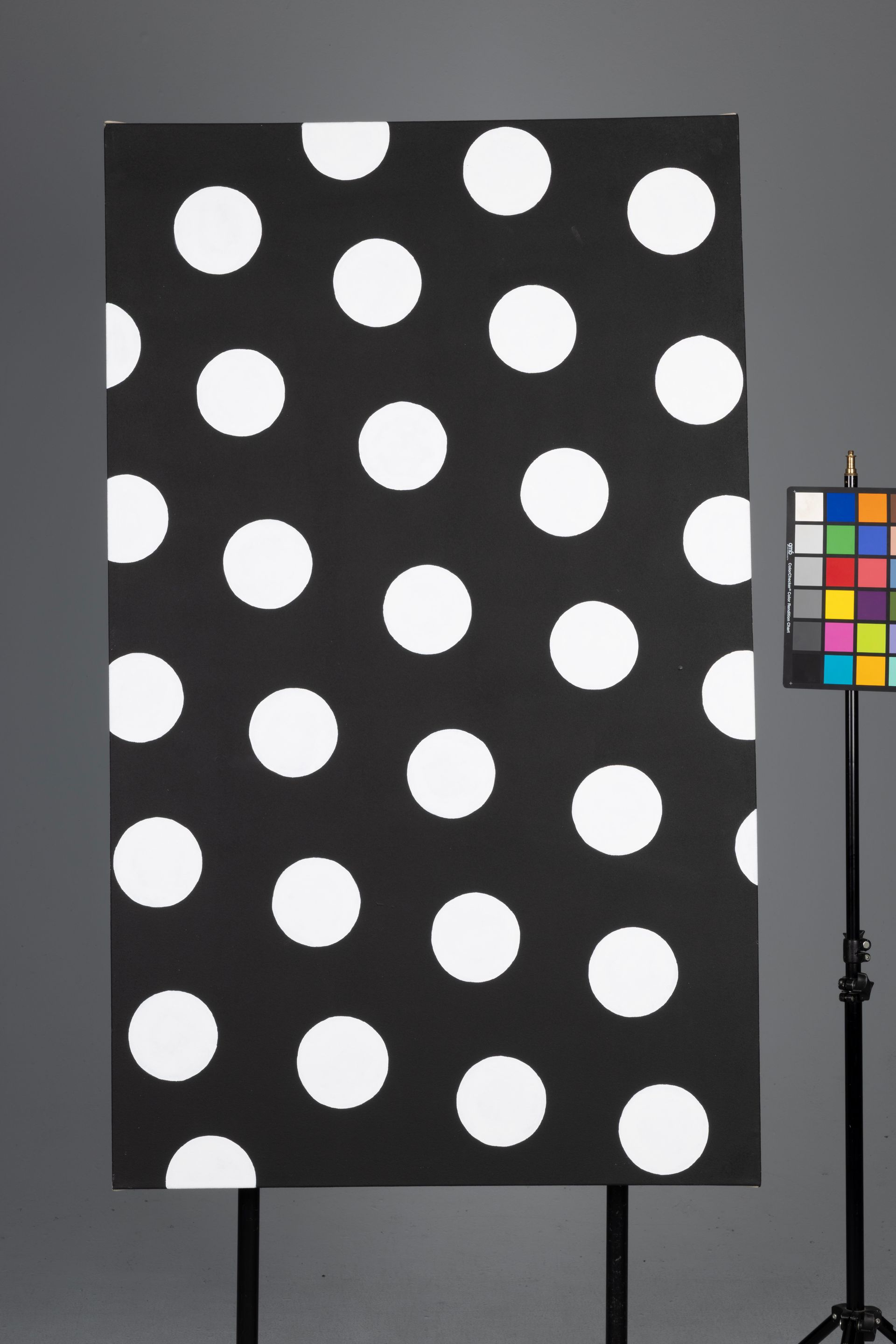 Black panel with large white polka dots on a gray background, beside a color calibration chart.