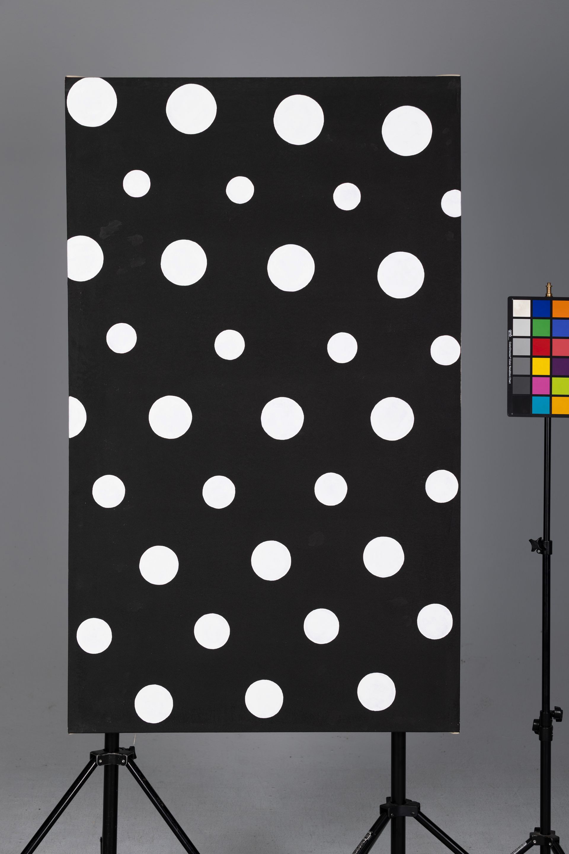 Black board with white polka dots on a tripod stand beside a color swatch chart.