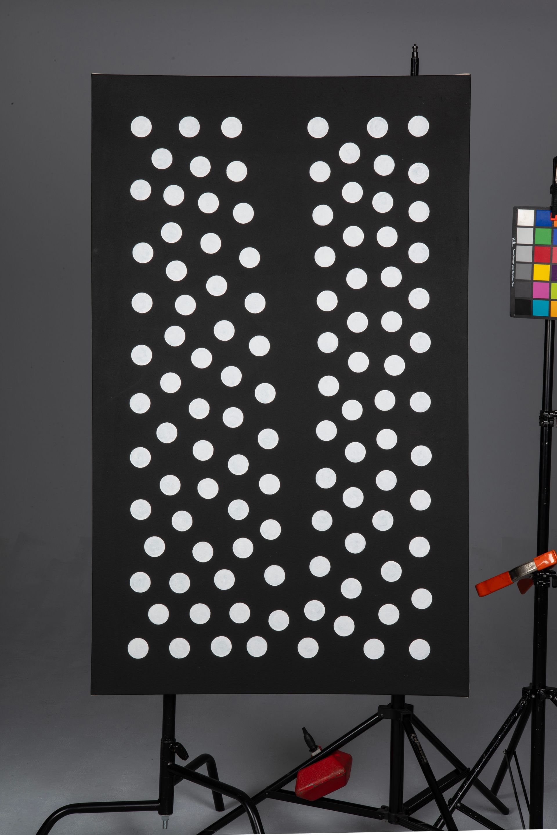 Black board with rows of white circular markers on a studio setup, with a color checker at right