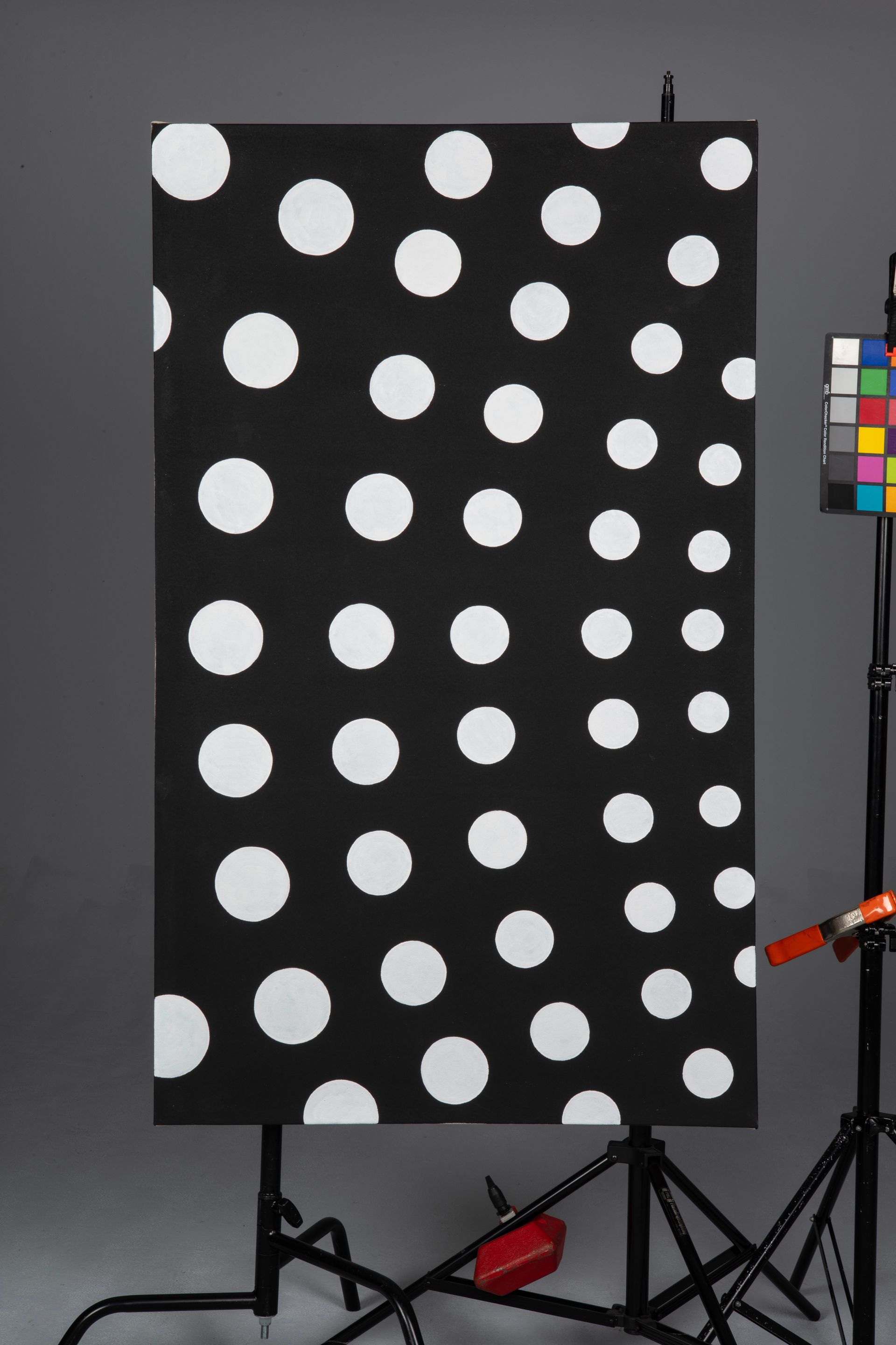 Black panel with white polka dots on a stand, with color calibration chart at right.