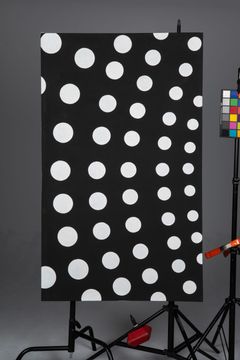 Black panel with large white polka dots on a stand in a studio, with color calibration chart at right.