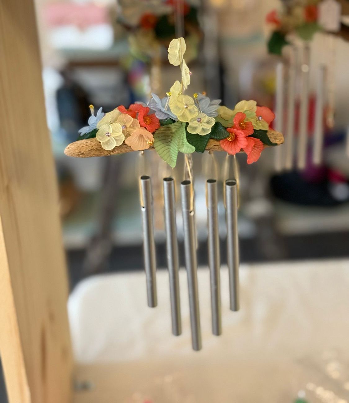 A wind chime with flowers hanging from it is sitting on a table.