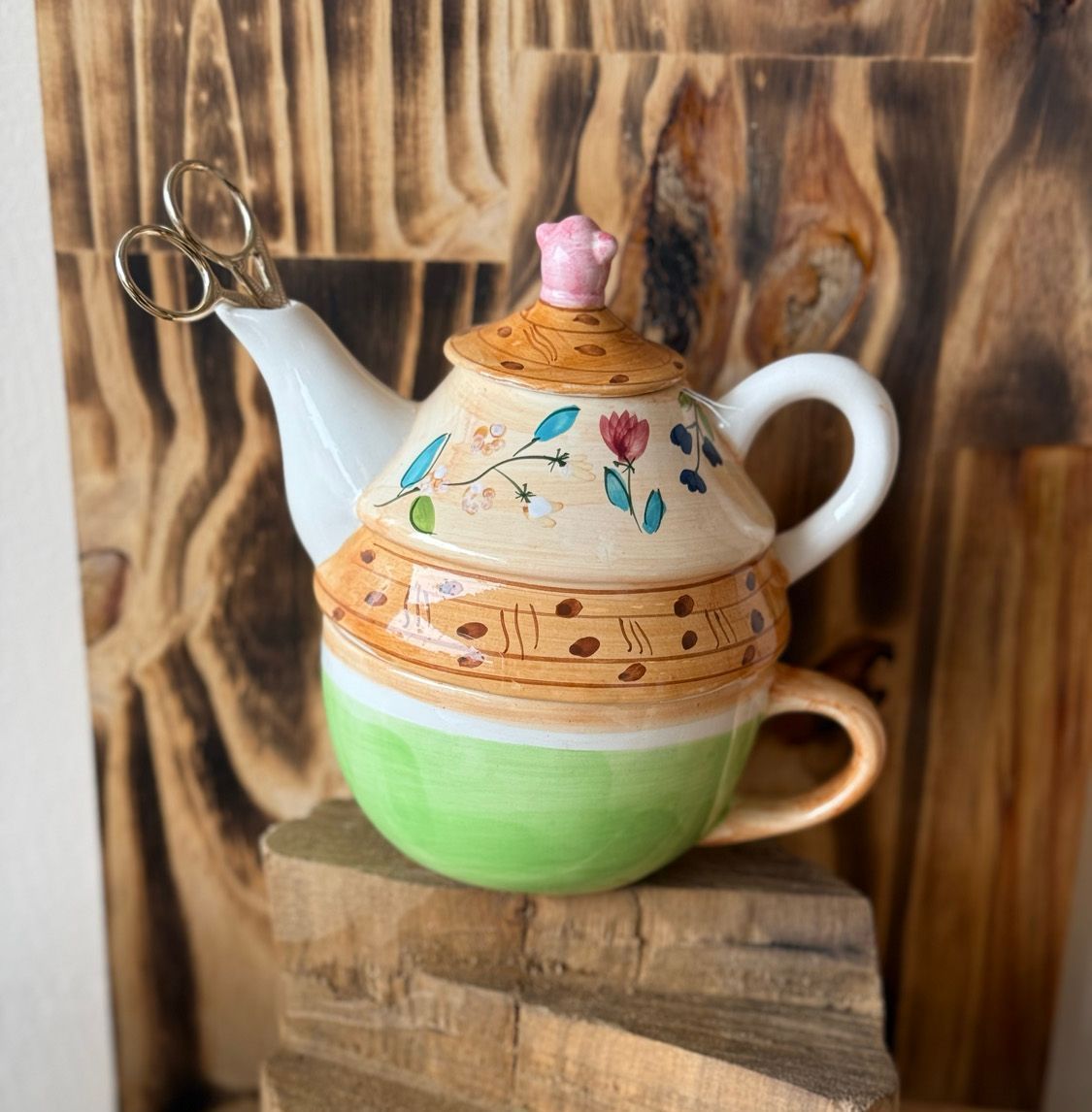 A teapot and cup are sitting on a wooden block