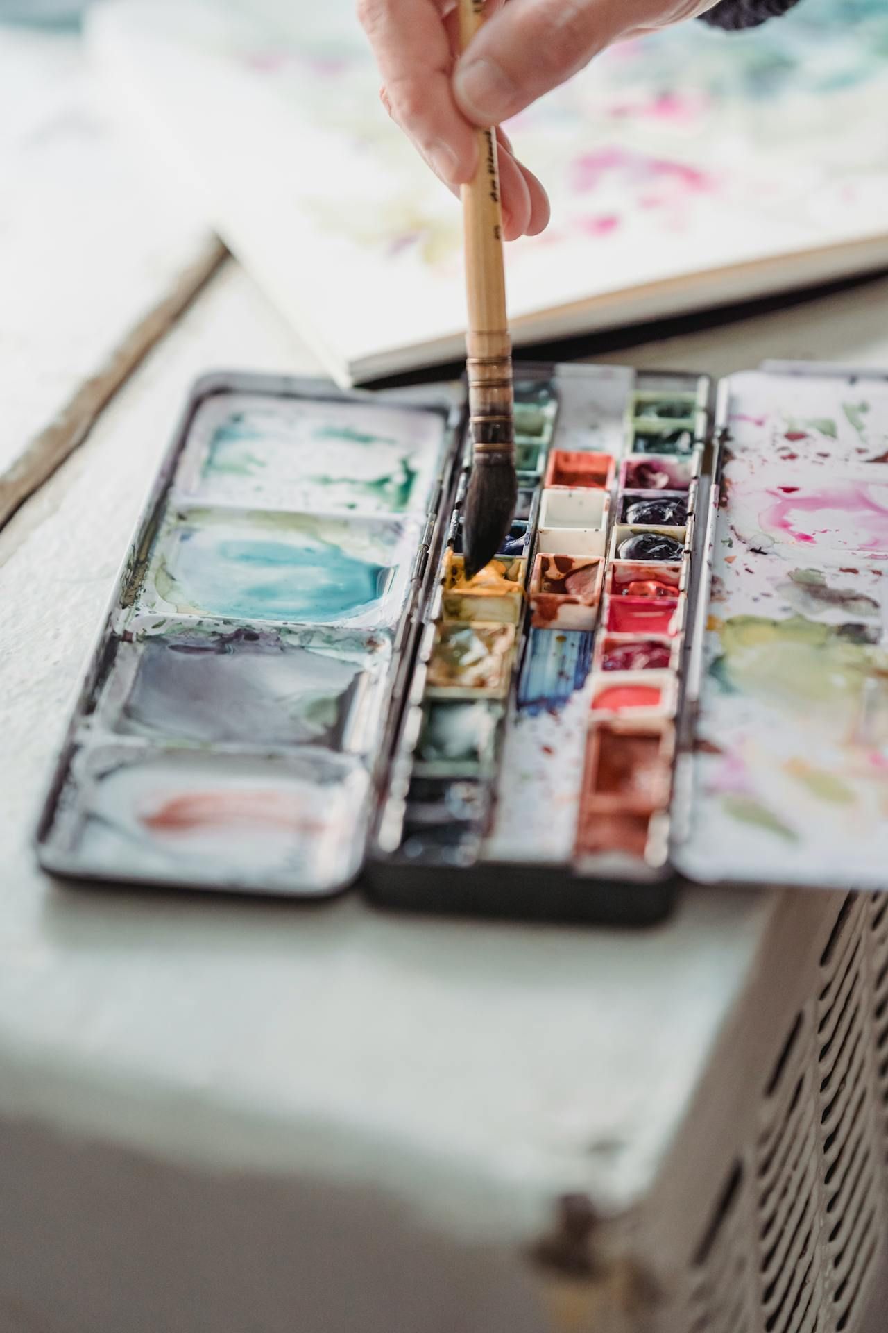 A person is painting with watercolors and a brush.